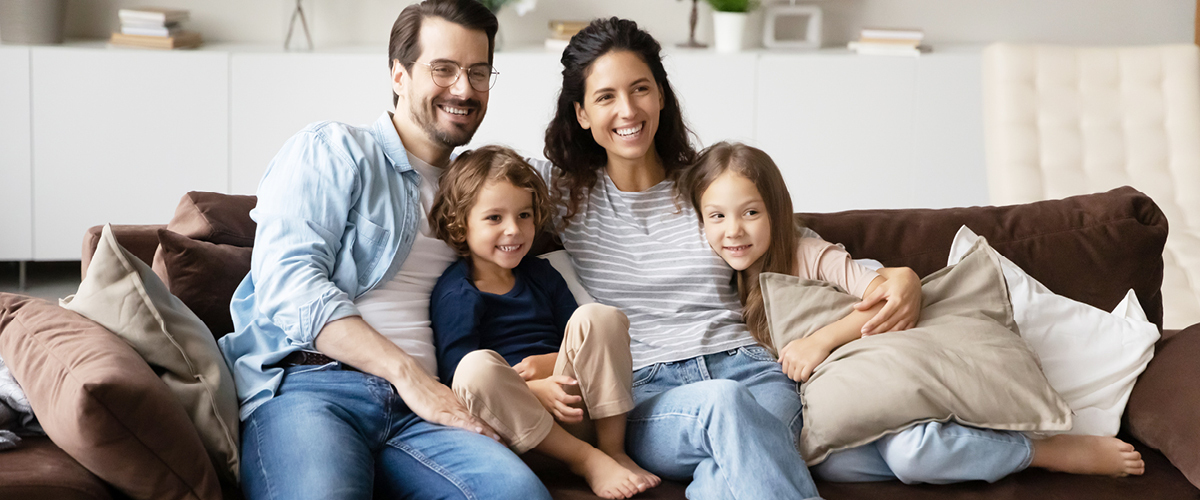 Family of four sitting together on the couch.