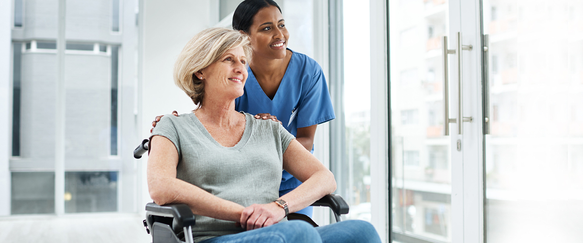 Medical professional pushing a patient in a wheelchair.