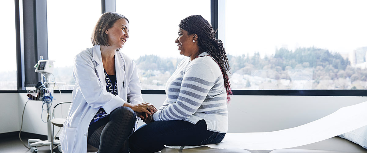 Woman speaking with a healthcare professional in a doctor's office.