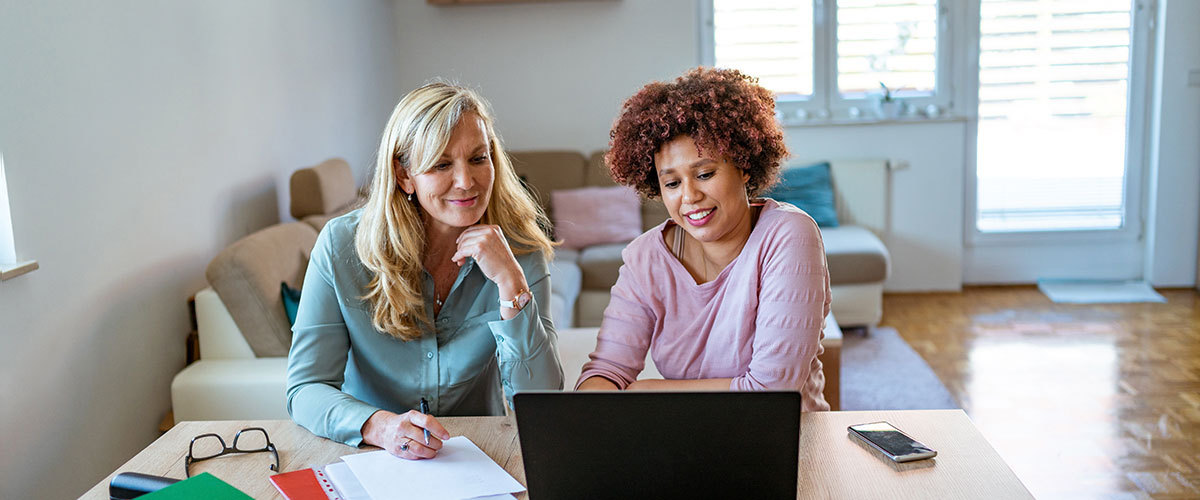 Two women sitting at a computer together.