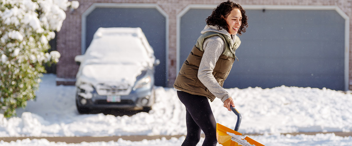 Woman shoveling snow off of her driveway.